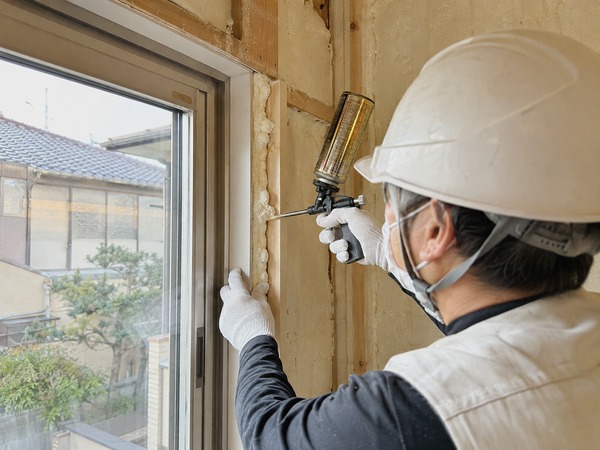 窓枠まわりに断熱充填材を施工する作業